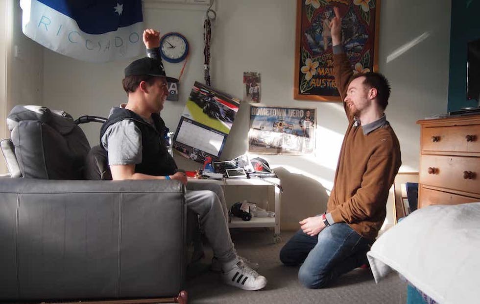 A Like Family Social Carer and Member facing opposite each other with one arm raised in the air