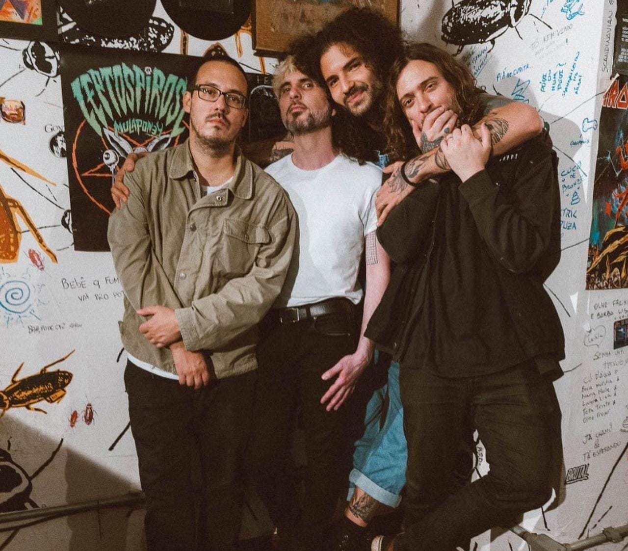 Banda Zander posando em frente a uma parede cheia de posters