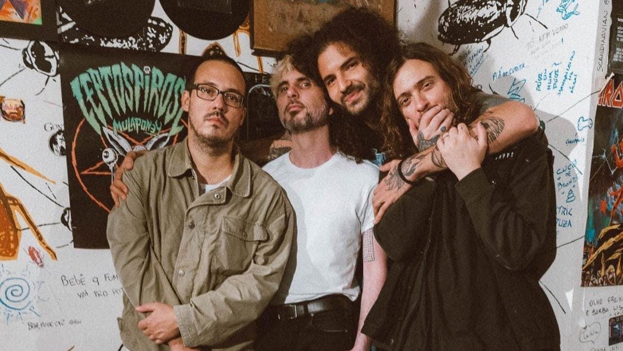 Banda Zander posando em frente a uma parede cheia de posters