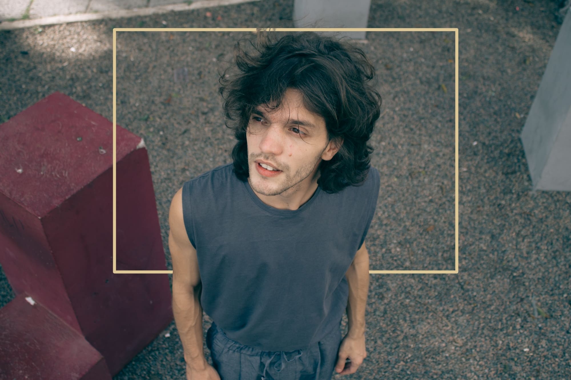 Didi Fiorucci aparece de blusa cinza, visto de cima para baixo. Os cabelos, lisos, estão desarrumados pelo vento. Ele olha para o lado.