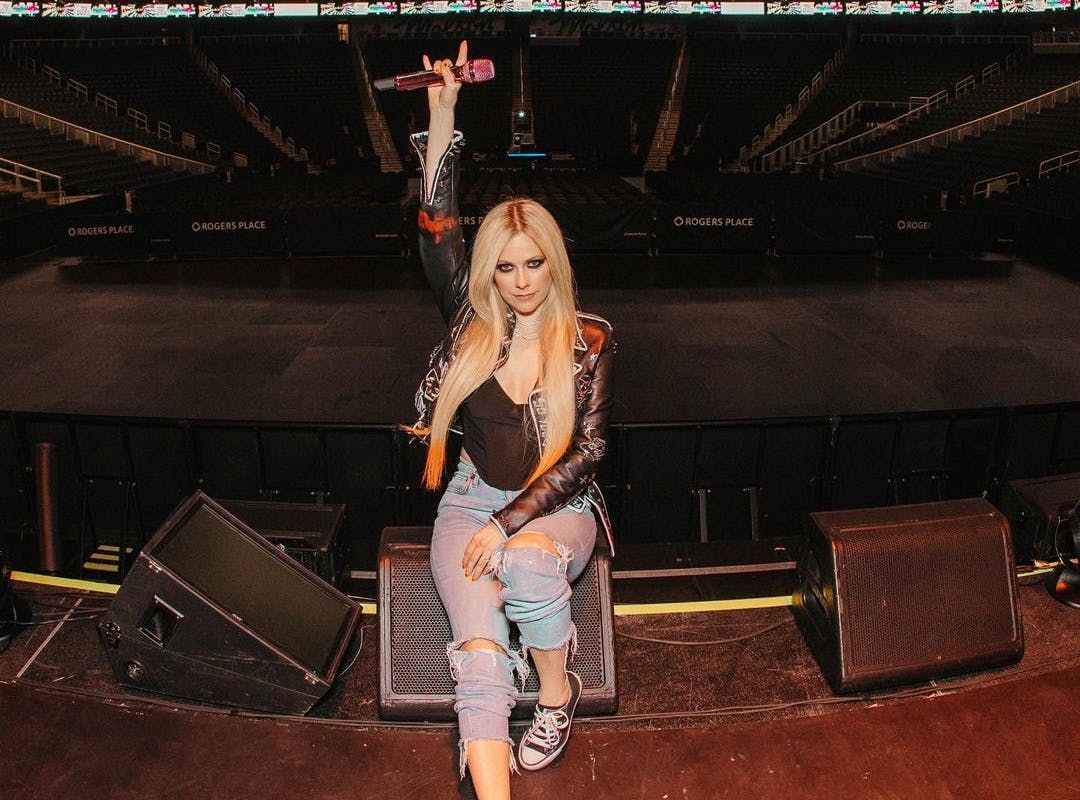 Avril Lavigne em cima do palco, com o microfone erguido