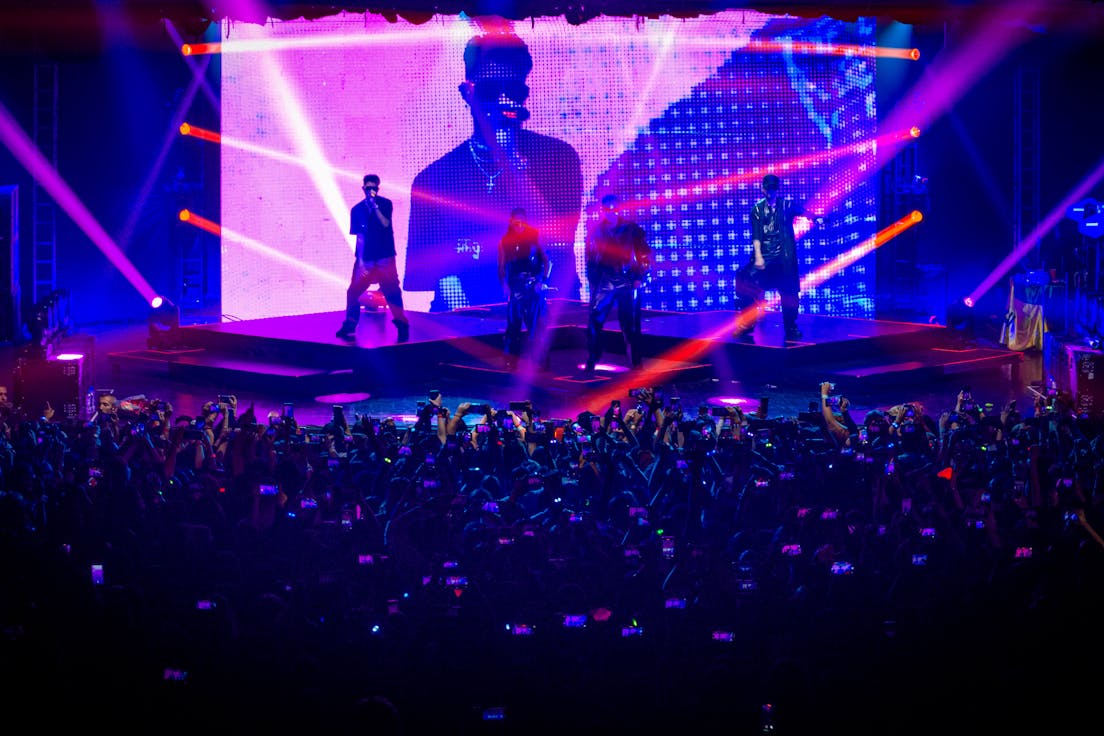 CNCO no Brasil. Imagem mostra palco visto de cima, com artistas no palco e plateia abaixo