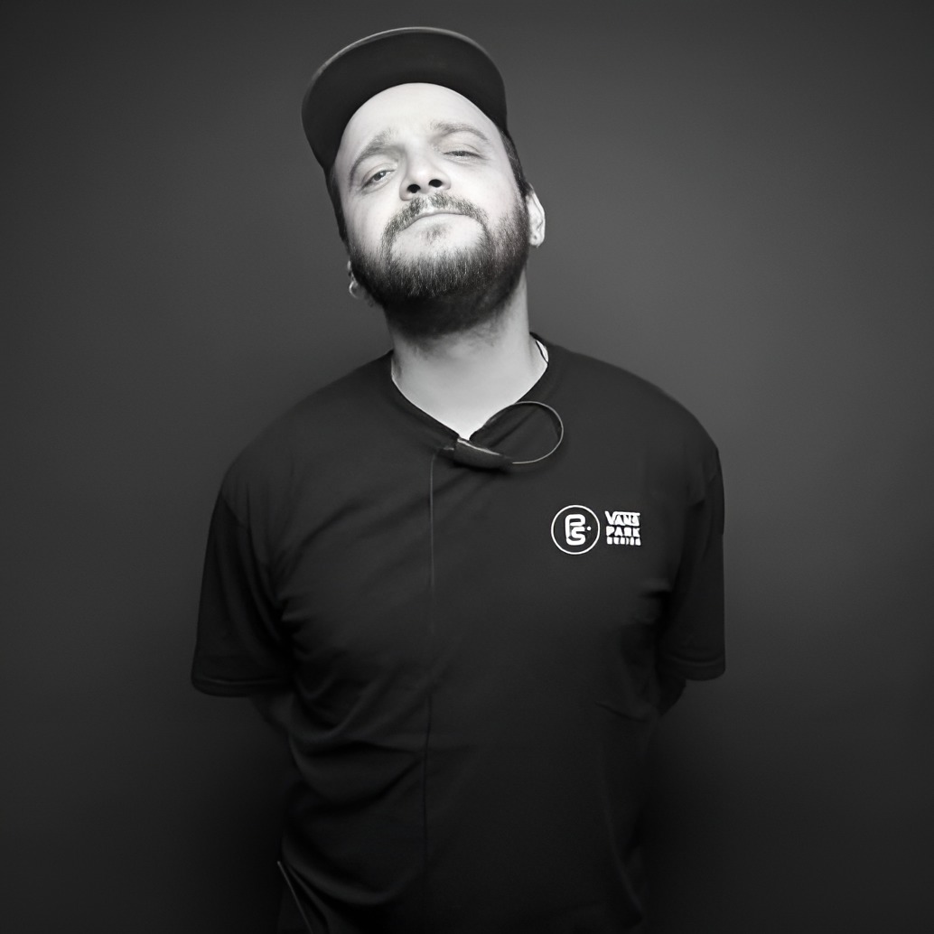 Rafael Pelegrino posa em um fundo preto e com roupa e boné preto também.