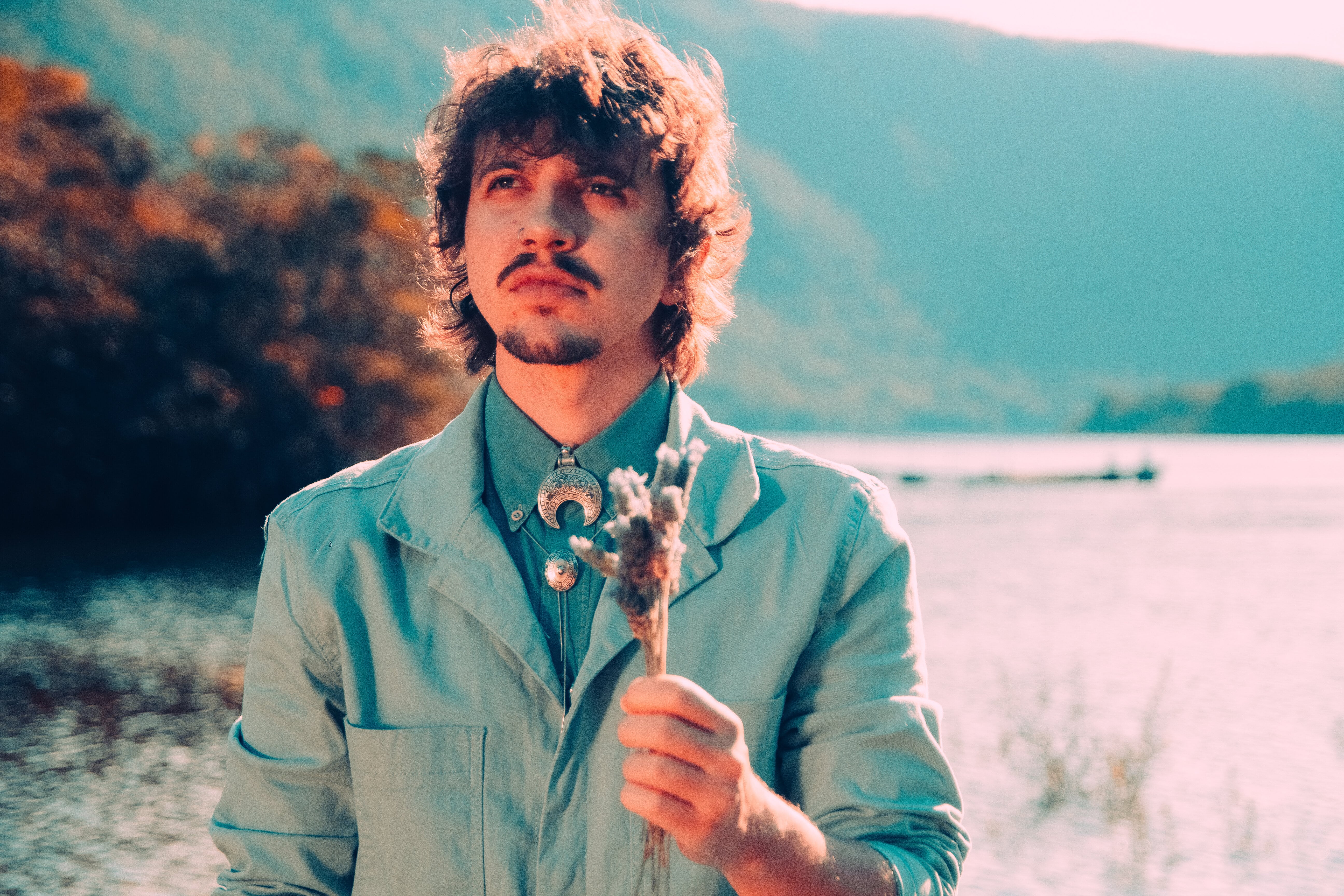 Eddu está de azul, segurando uma lavanda e olhando para cima, não para a câmera