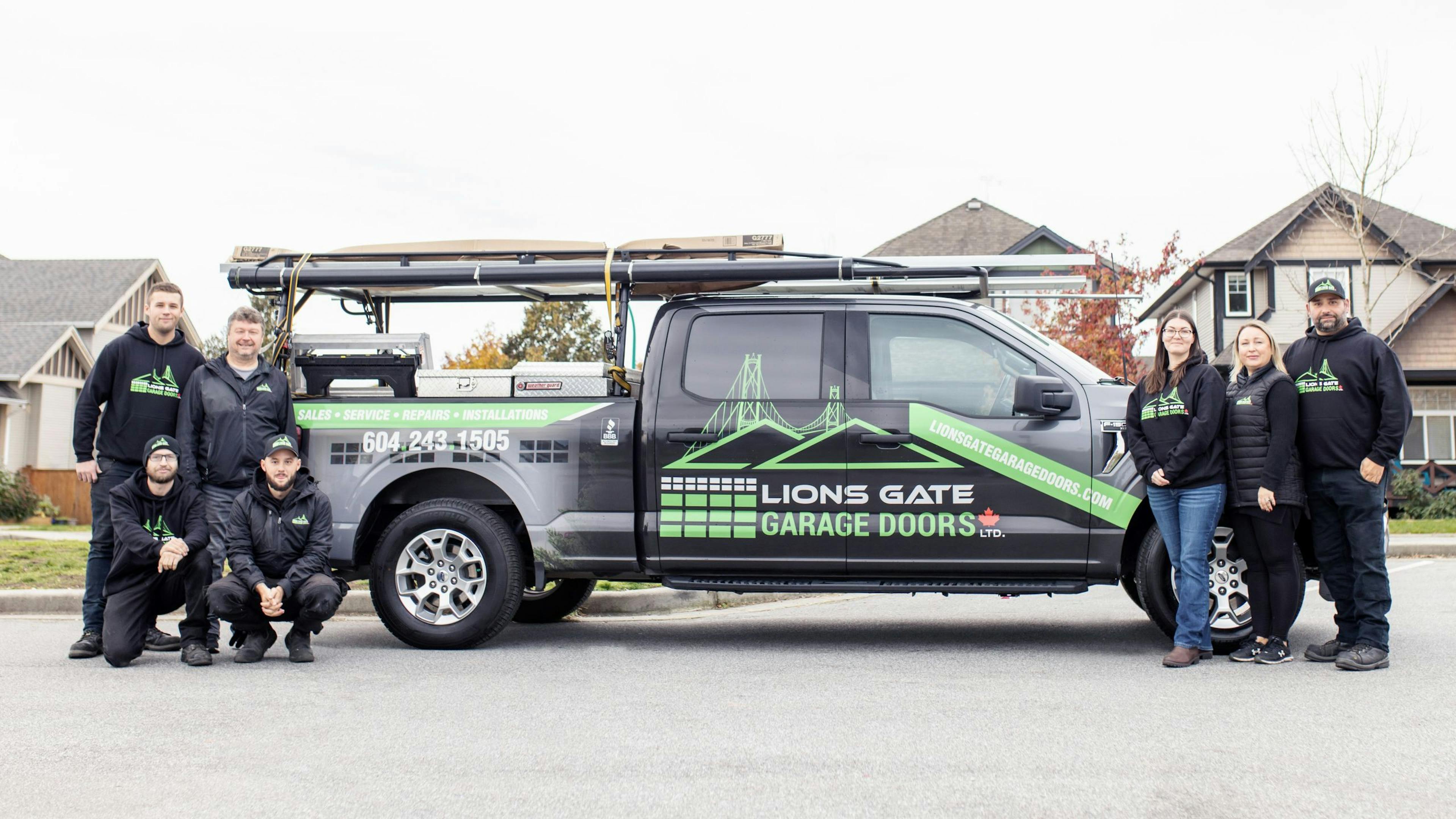The Lions Gate Garage Door team stands smiling with their truck.