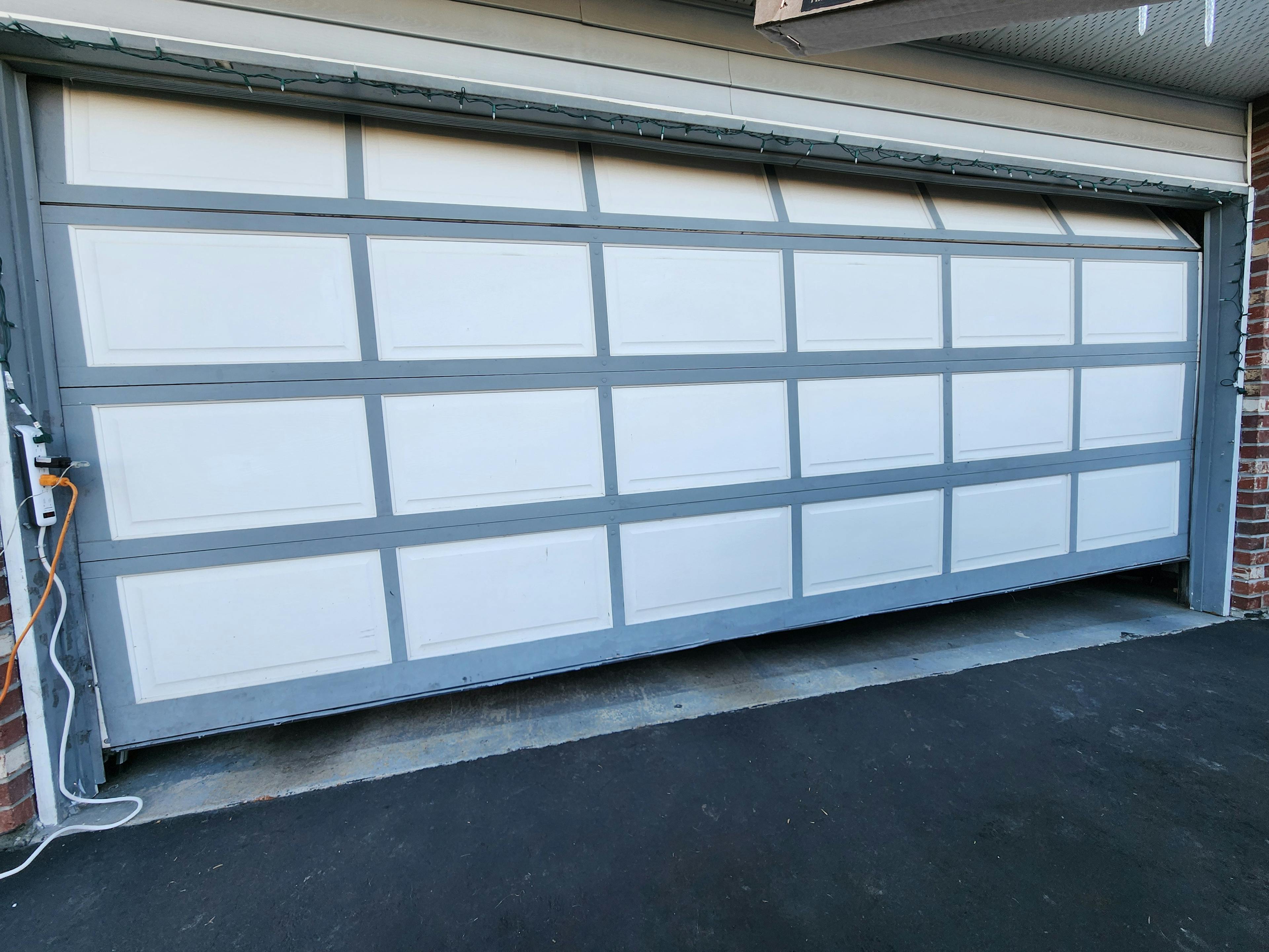 A crooked garage door was bumped by a car.