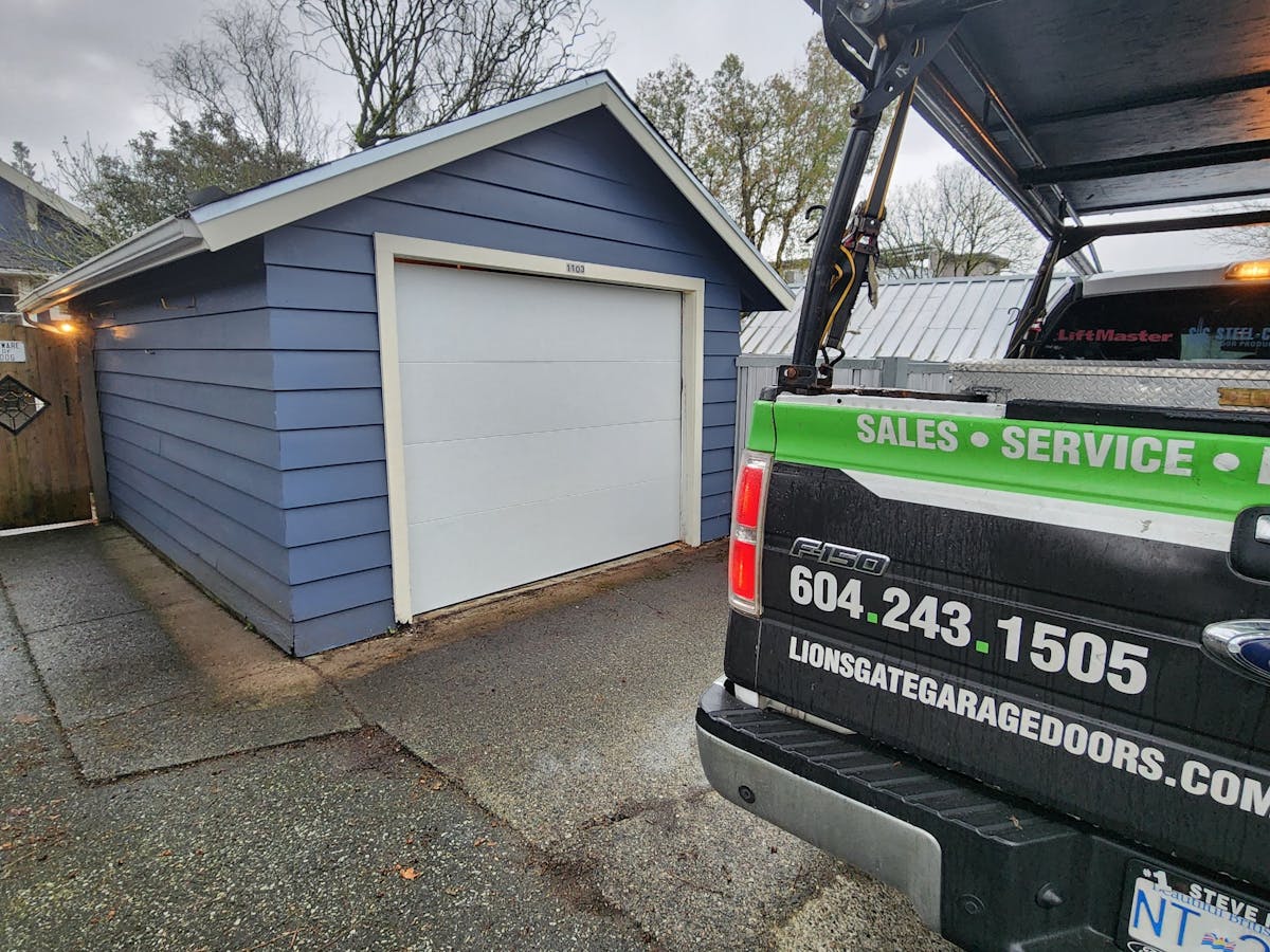 An new white garage door is replacing and old door by Lions Gate Garage Doors LTD.