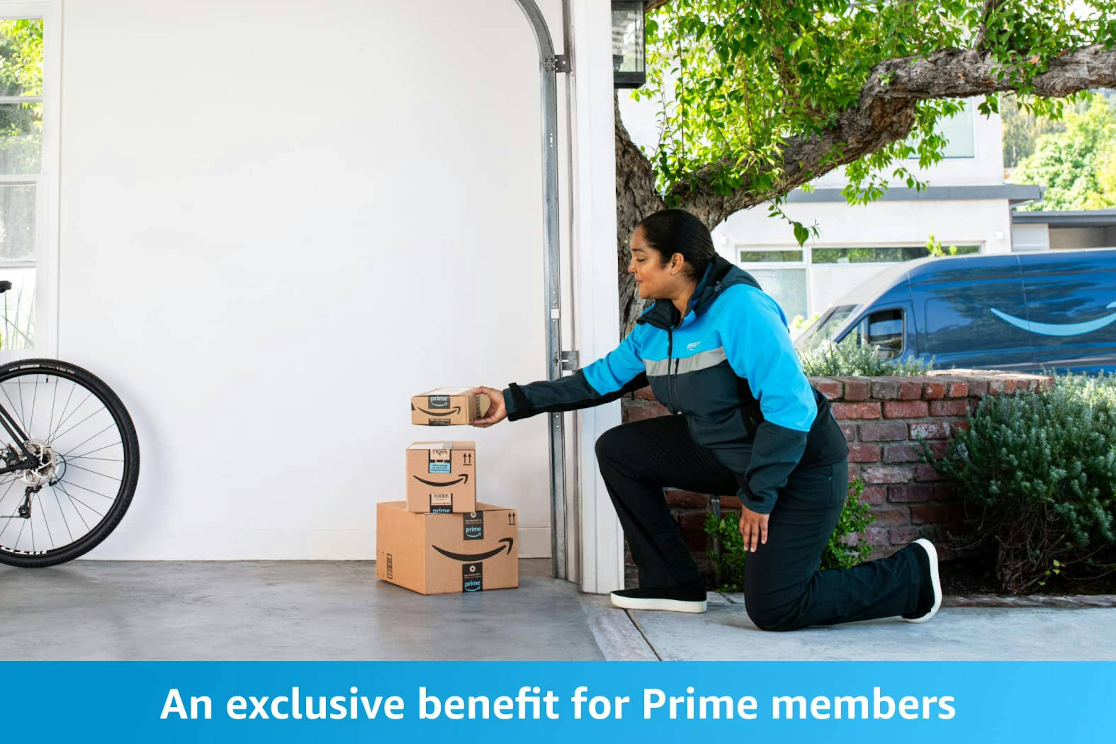 An exclusive benefit for Amazon Prime members. An Amazon delivery associate is placing cardboard boxes inside a customer's garage.