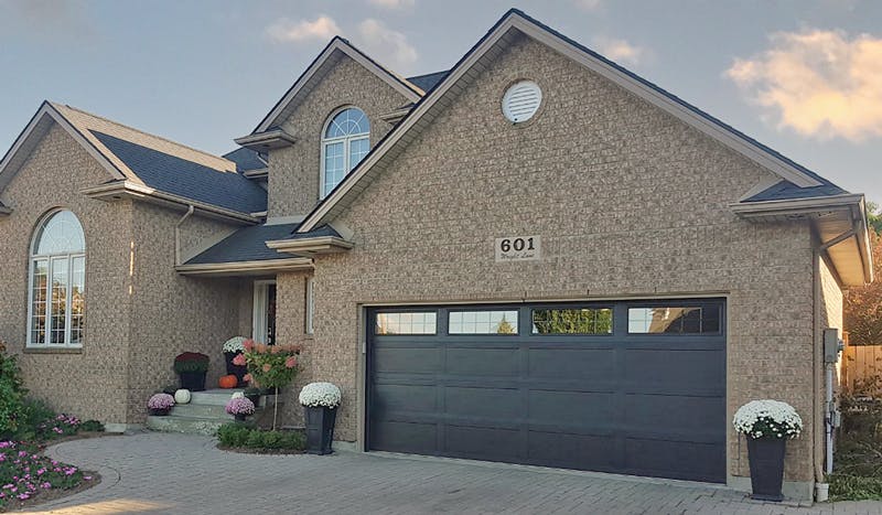 A brick home with a black Northland R12 garage door