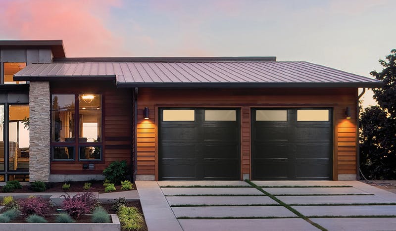 A one-story home with two black Northland R18 garage doors