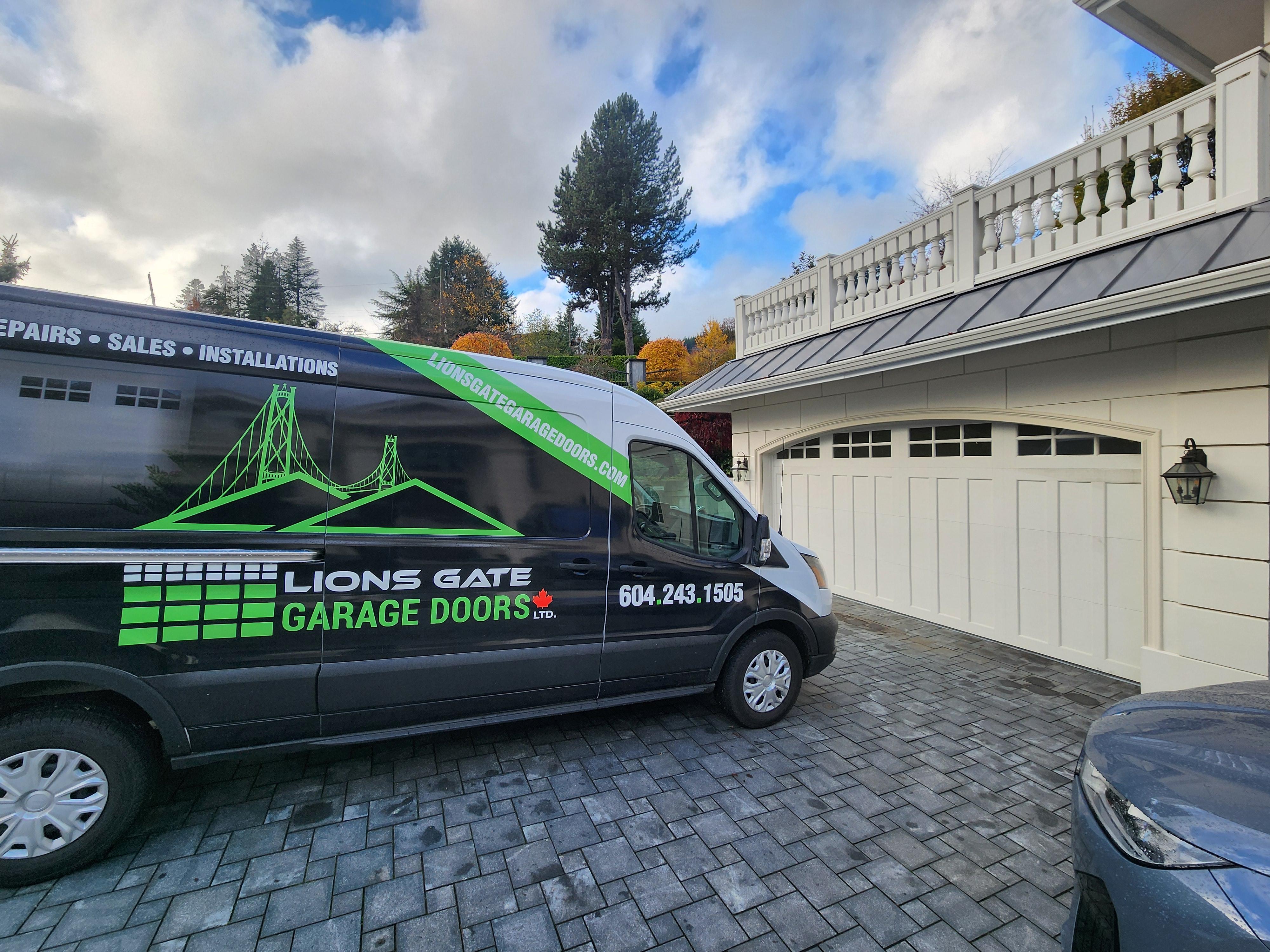 Repaired garage door with Lions Gate Garage Doors' Van in foreground