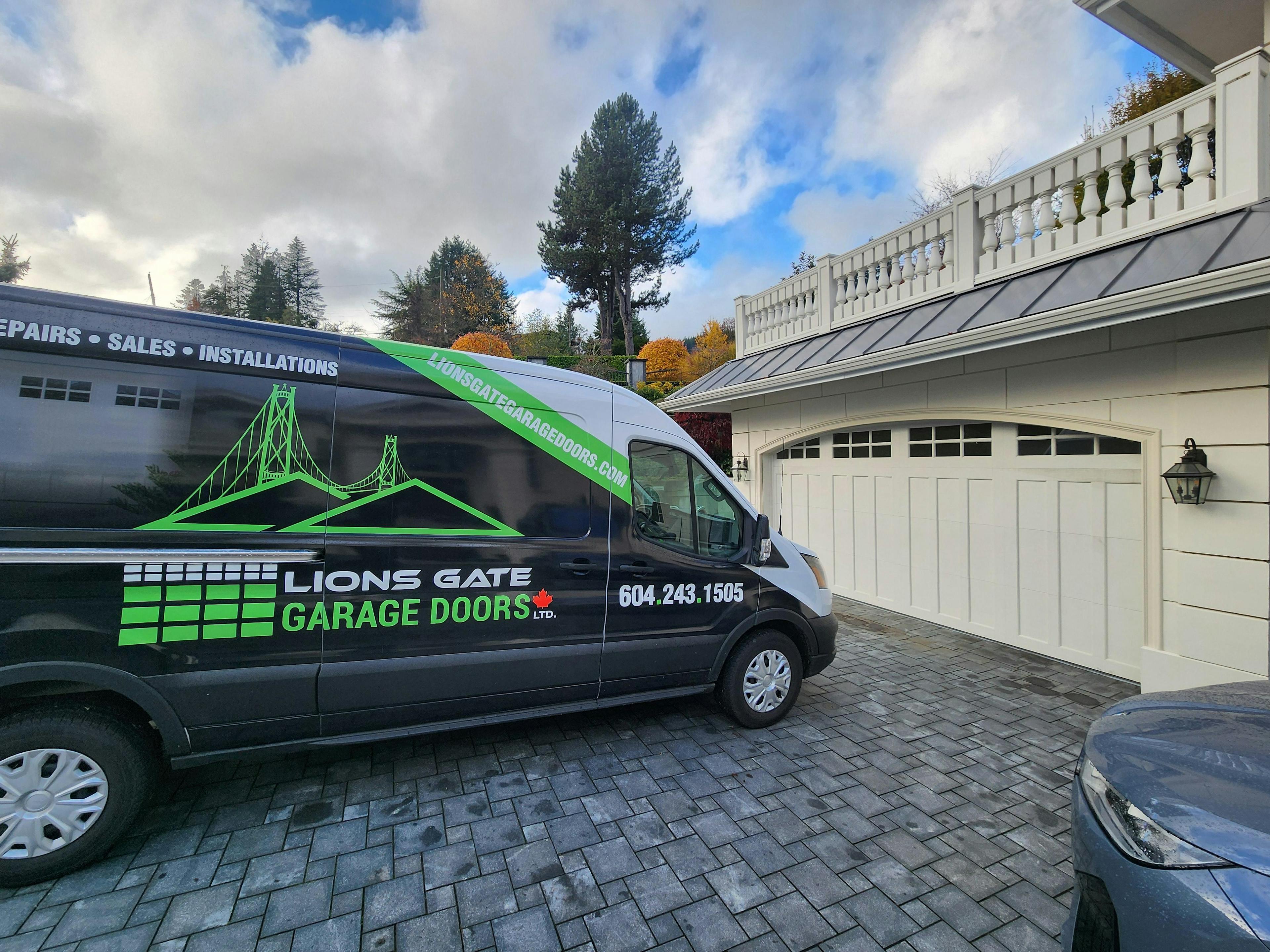 Repaired garage door with Lions Gate Garage Doors' Van in foreground