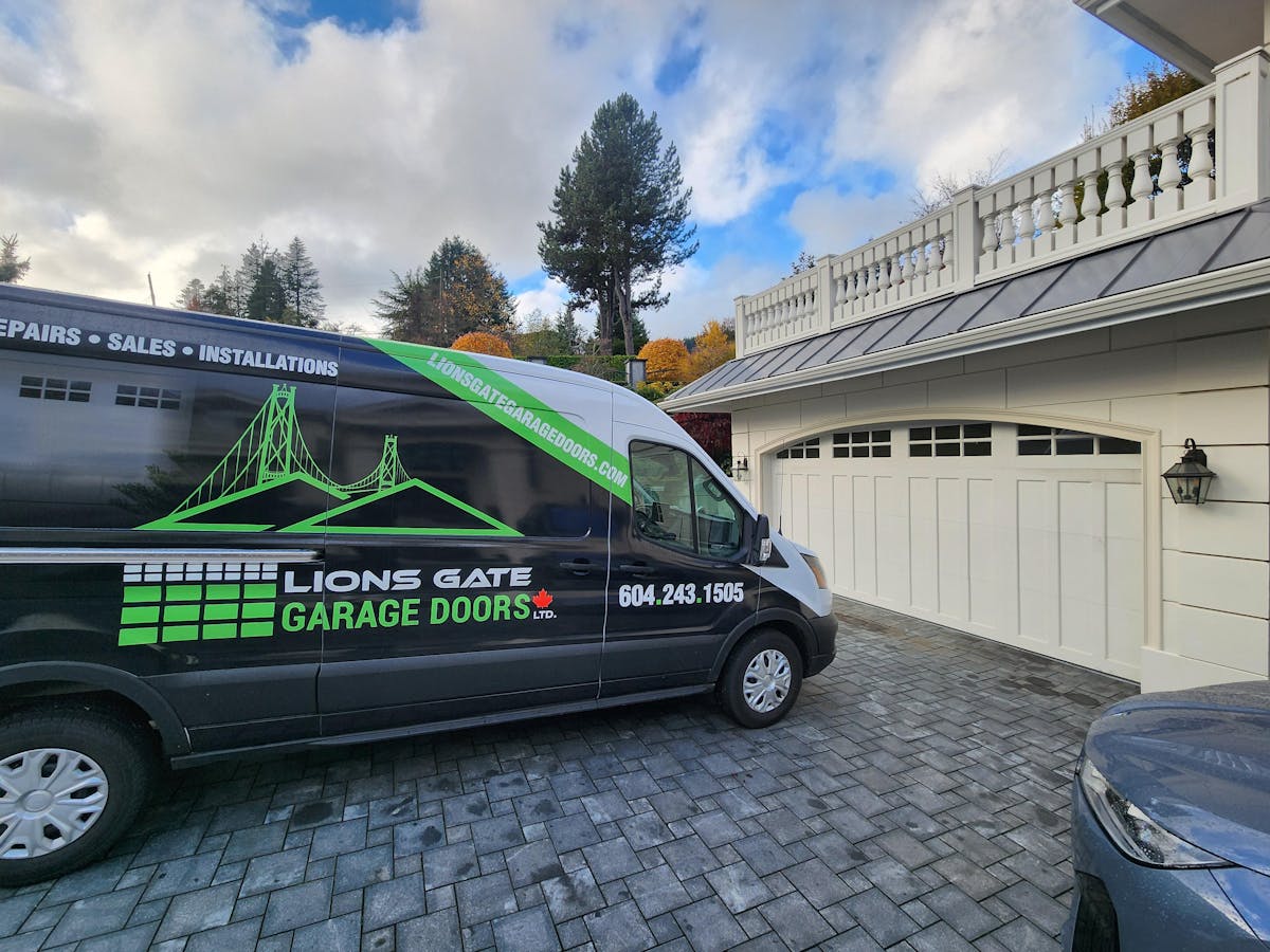 Repaired garage door with Lions Gate Garage Doors' Van in foreground