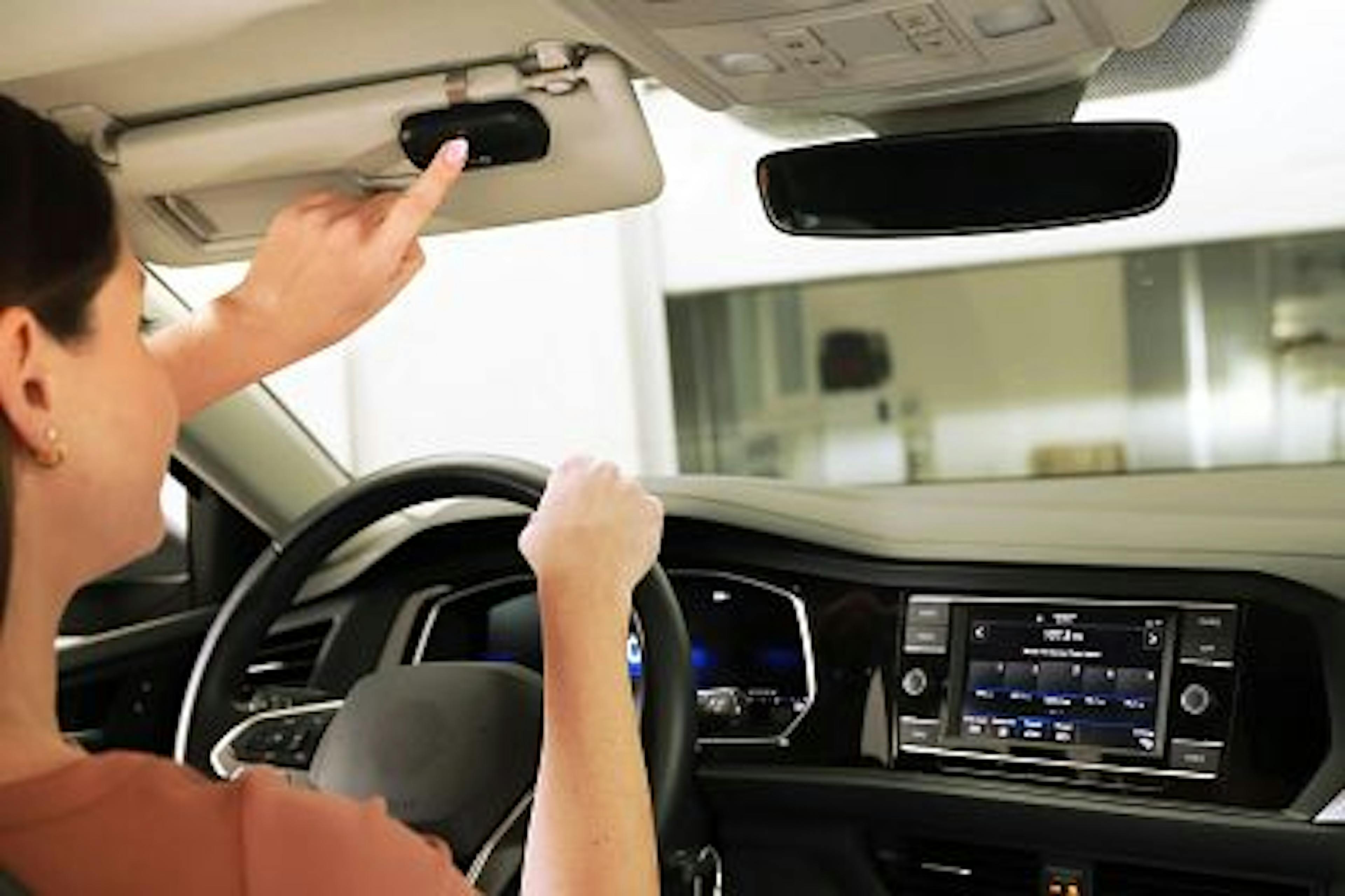 woman pusing the LiftMaster 3-Button Remote while on car visor