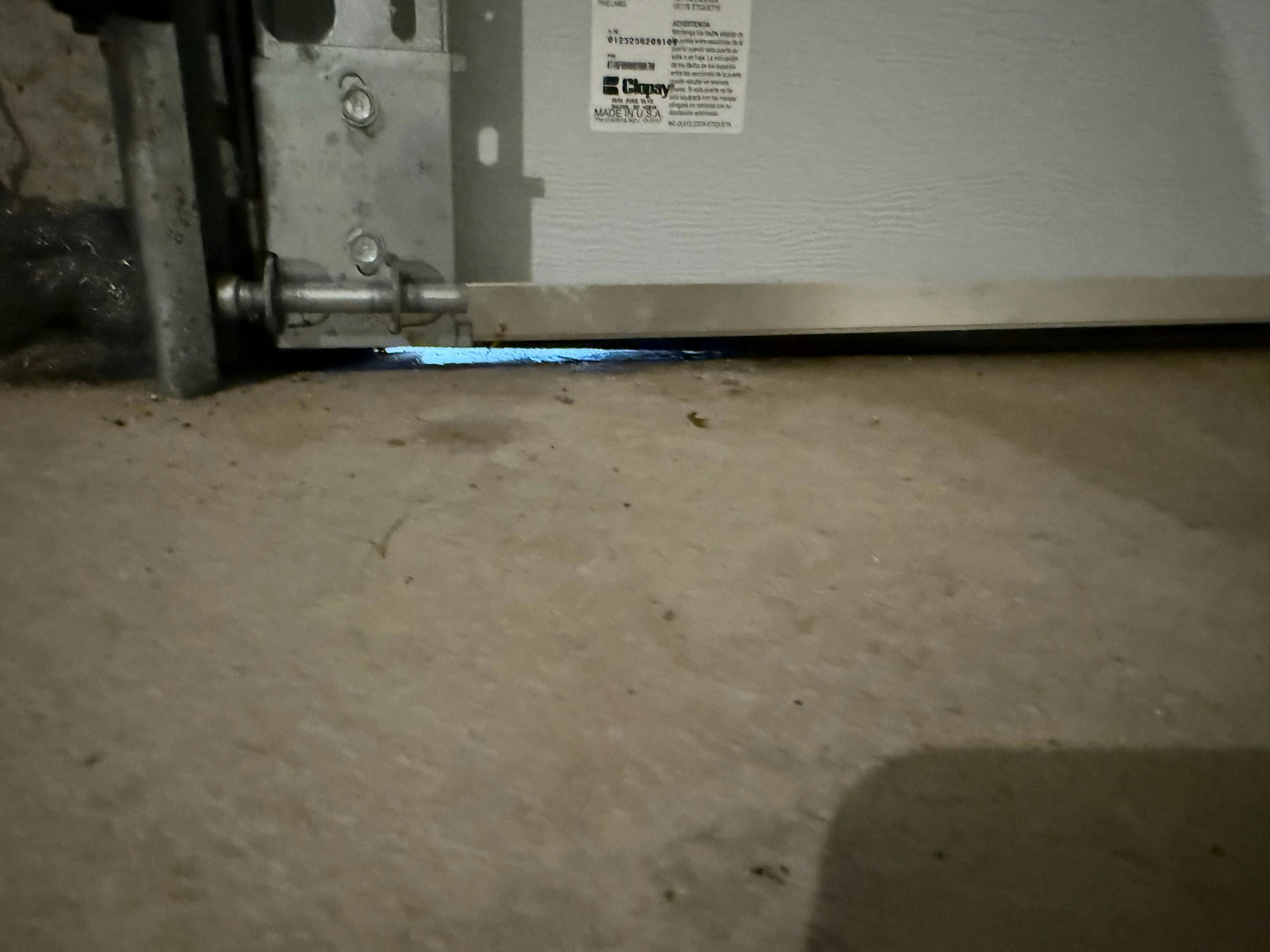 close-up of a garage door with daylight coming in from the bottom right corner providing space for pests to enter