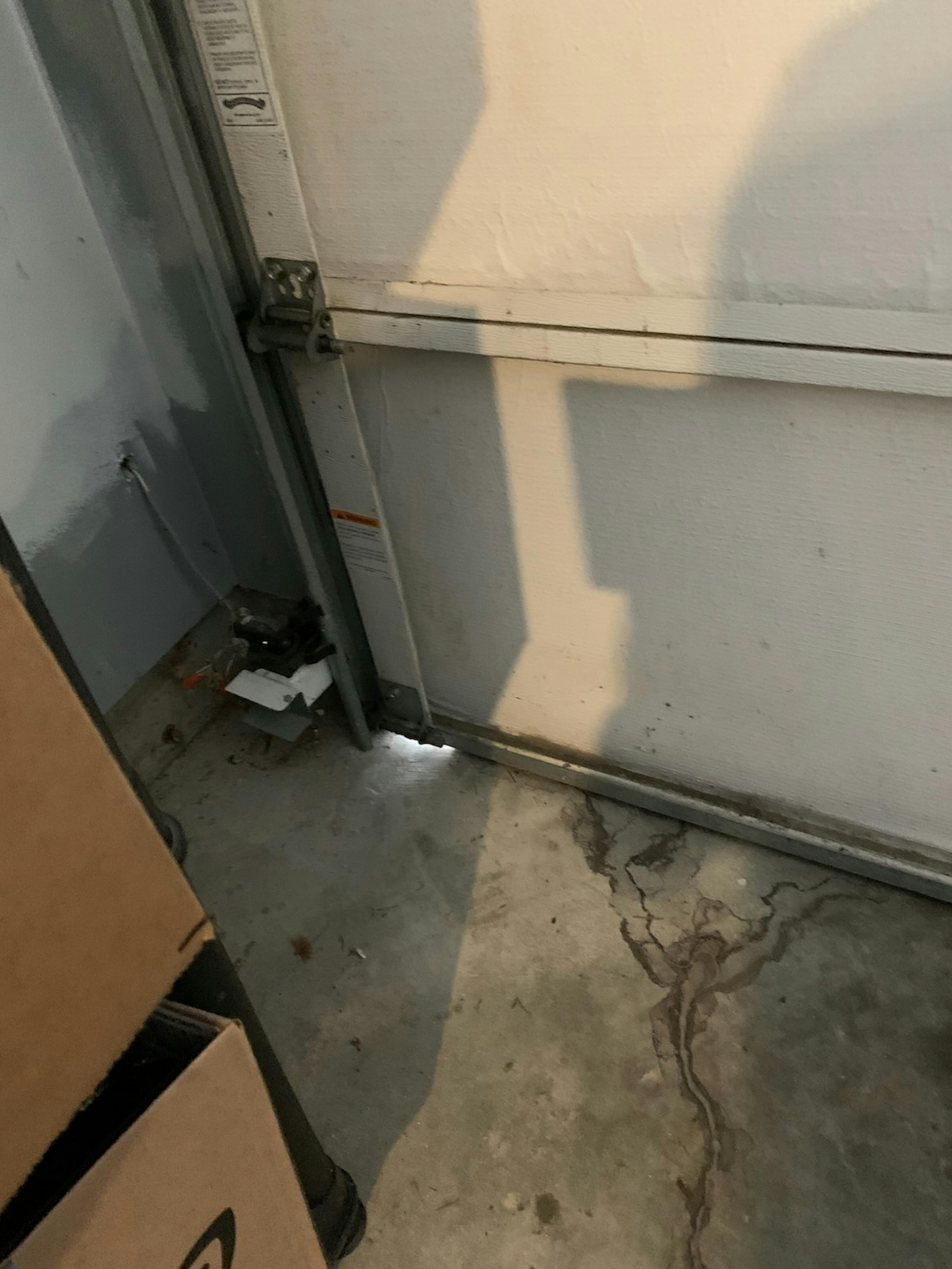 A garage door with a gap at the bottom left, allowing light to enter