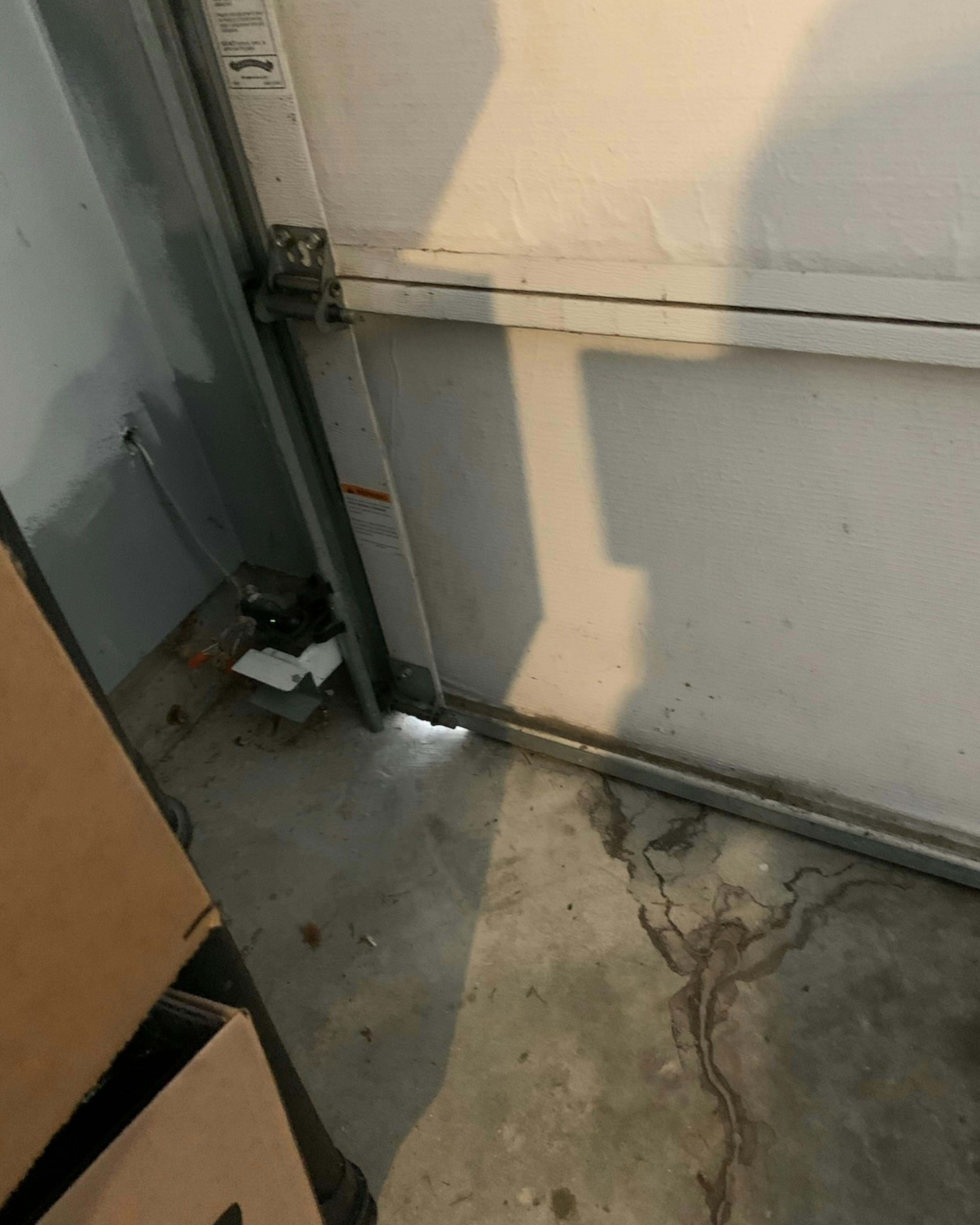 A garage door with a gap at the bottom left, allowing light to enter A garage door with a gap at the bottom left, allowing light to enter