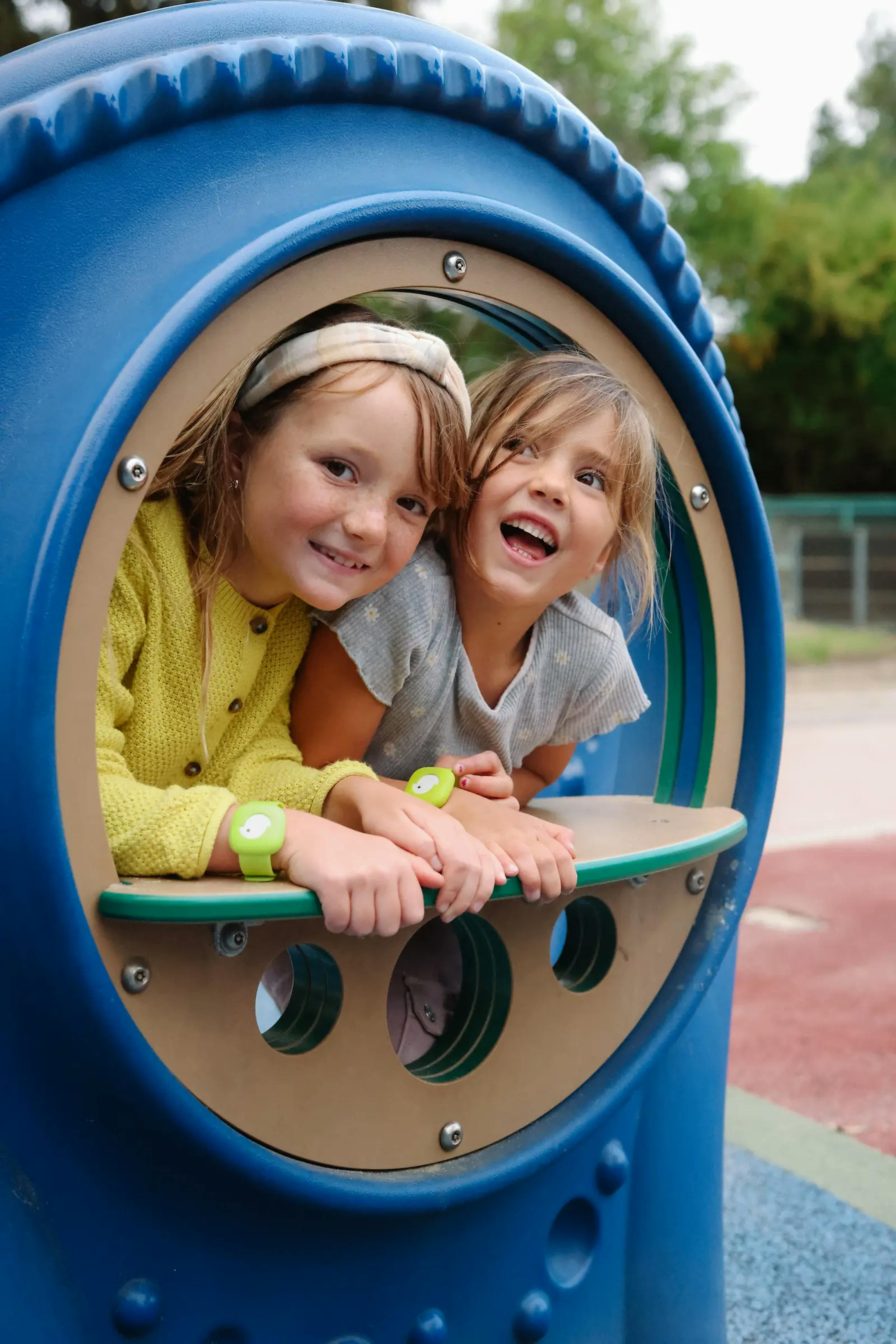 Girls peeking out of a window at a playground