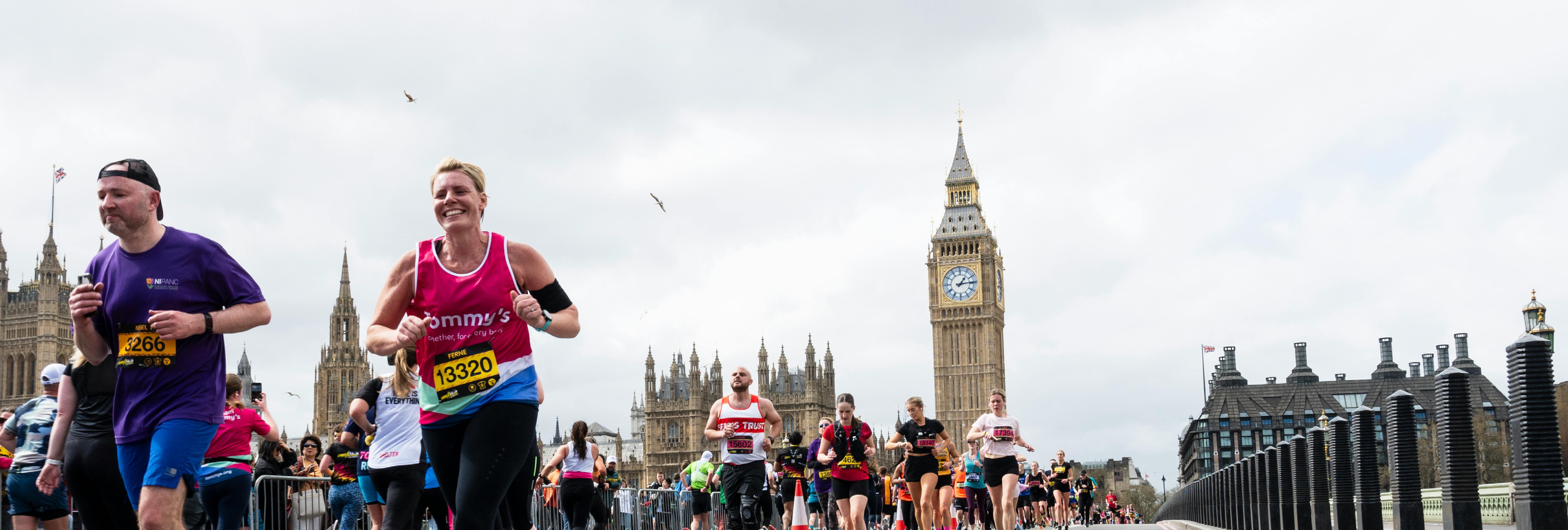 Man running the LLHM in pink Tommy's top, running past big ben.