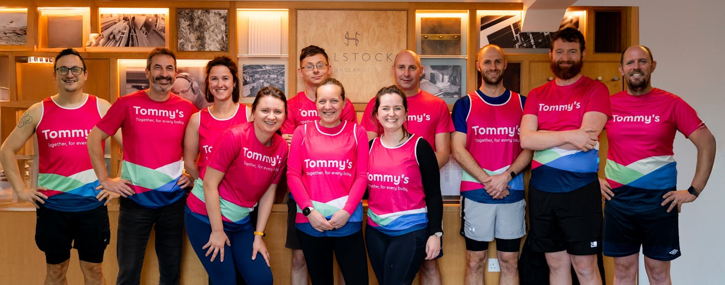 A group of runners smiling in pink Tommy's branded running tops
