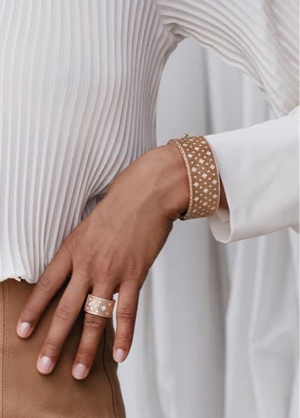 Women's hand modeling a cigar shaped sing with diamond quatrefoil design and coordinating cuff made of the same design with diamond quatrefoil.