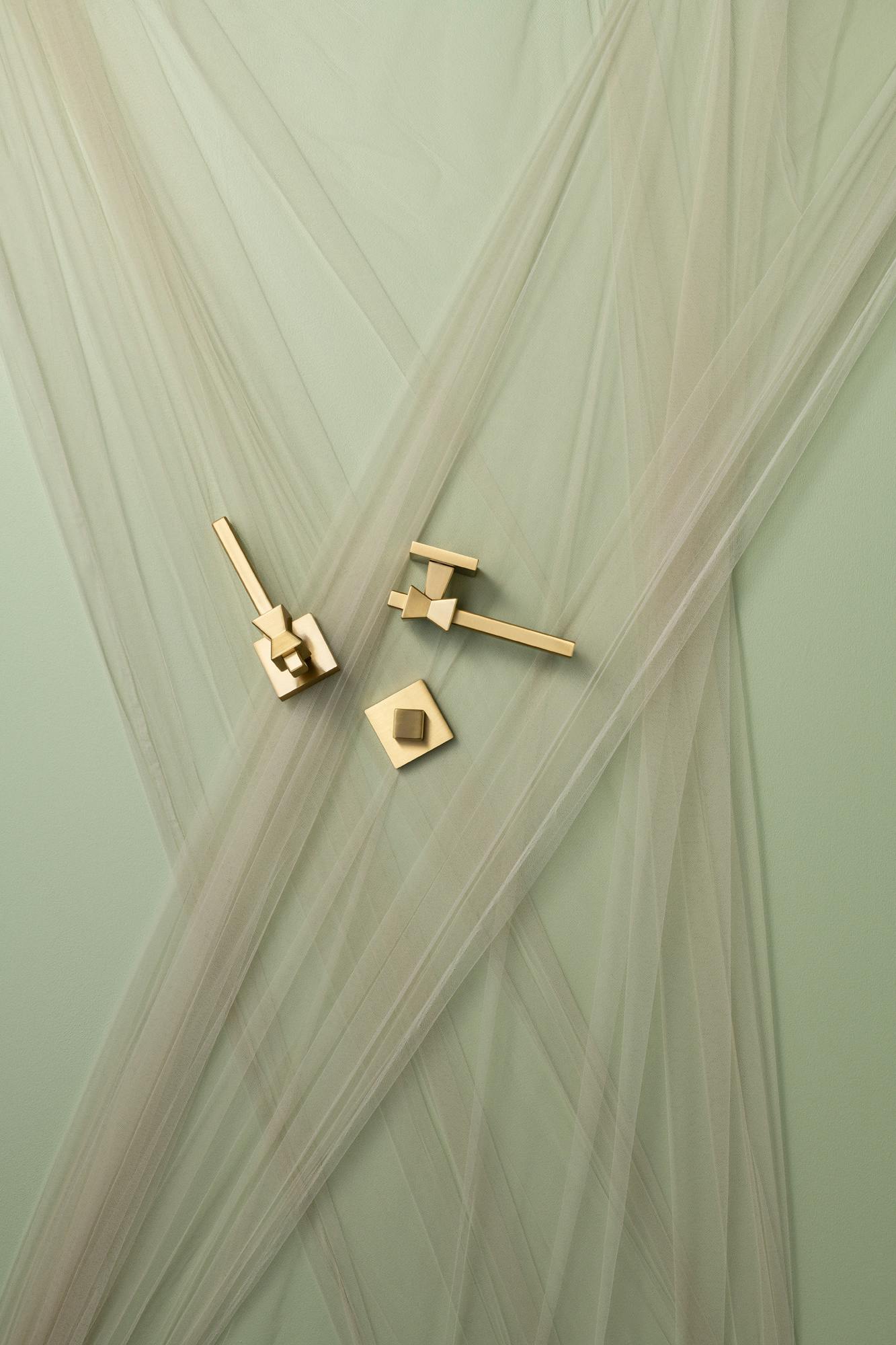 lo and co forma brass hardware on a green background surrounded by mesh