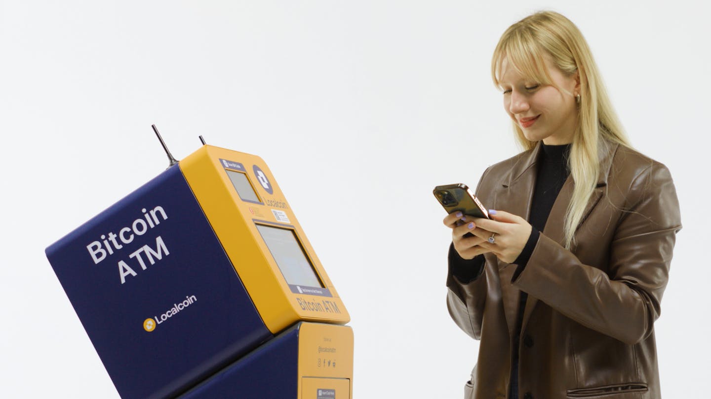 User checking phone beside Localcoin ATM