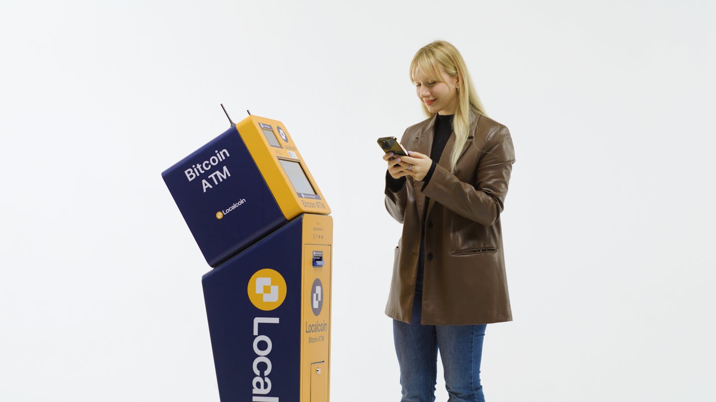User checking phone beside Localcoin ATM