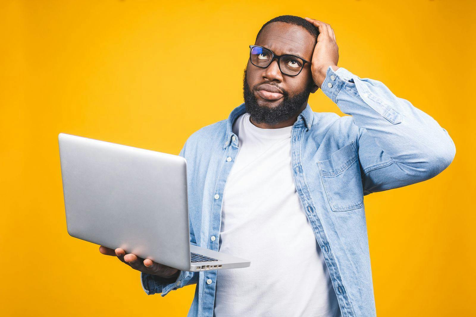 a confused man holding a laptop while researching myths on employee relocation