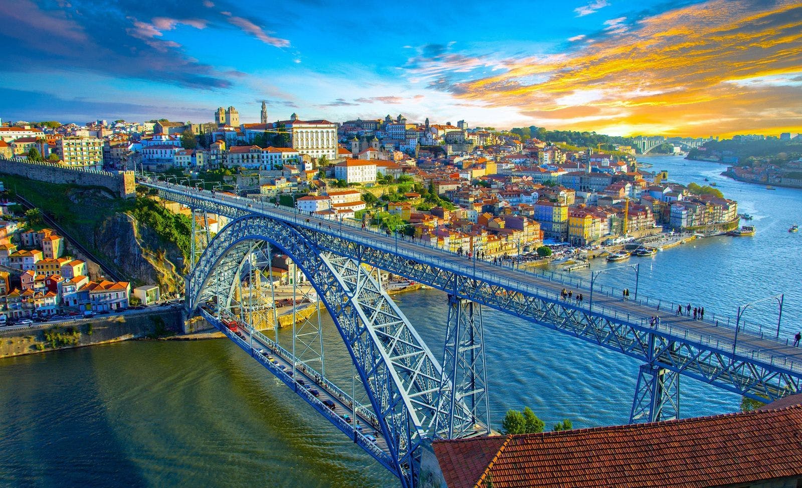 Bridge over a river leading to a city at sunset