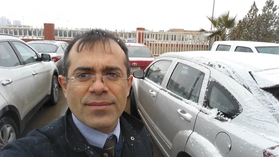 Ramazan, who requested asylum in the Netherlands, standing in a parking lot with cars