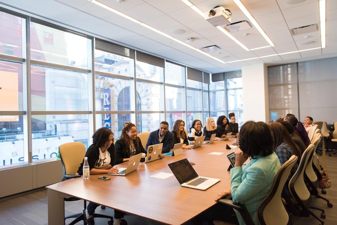 a diverse team of global talent sit at a conference table together, smiling