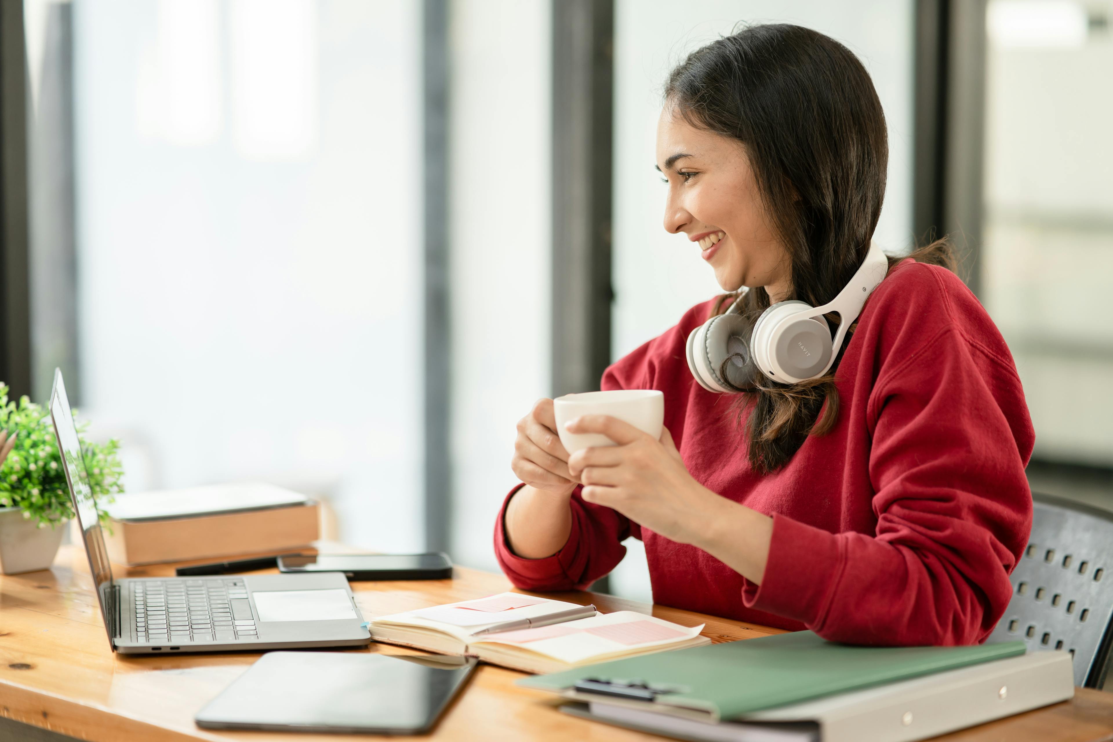 woman applying for visa from her laptop while holding a cup of coffee