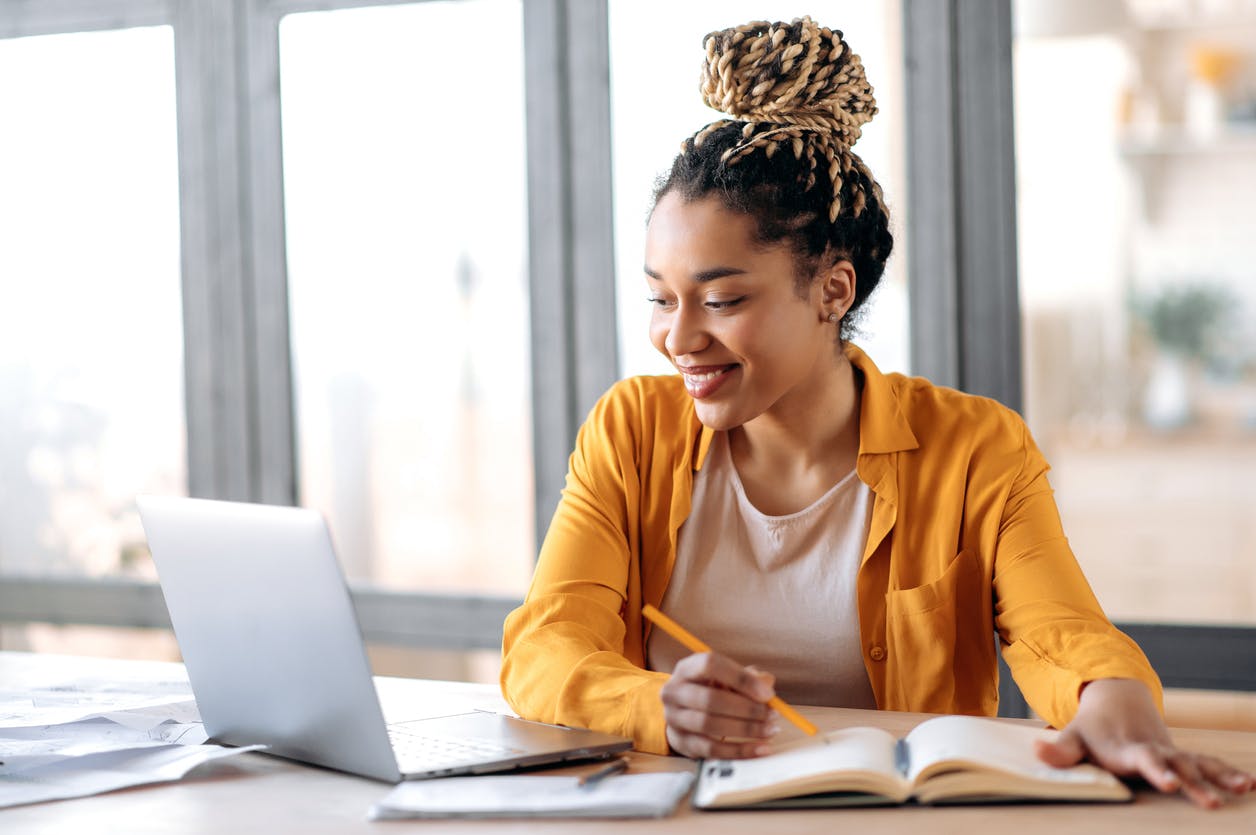 woman puts together a workforce plan while working on her laptop and notebook