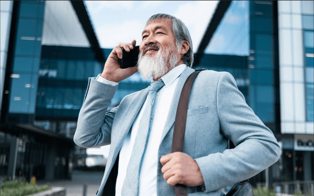 an older, Asian man in a business suit talking on his cellphone after arriving in the US on a B-1 visa