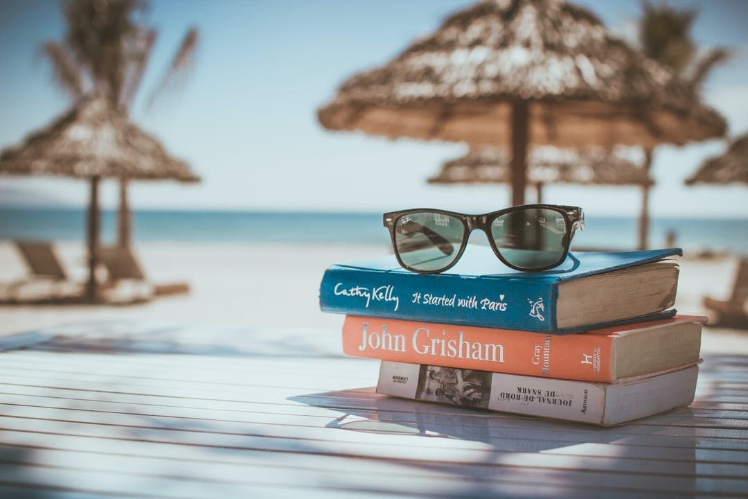 workation: where work meets vacations - a stack of books on the beach