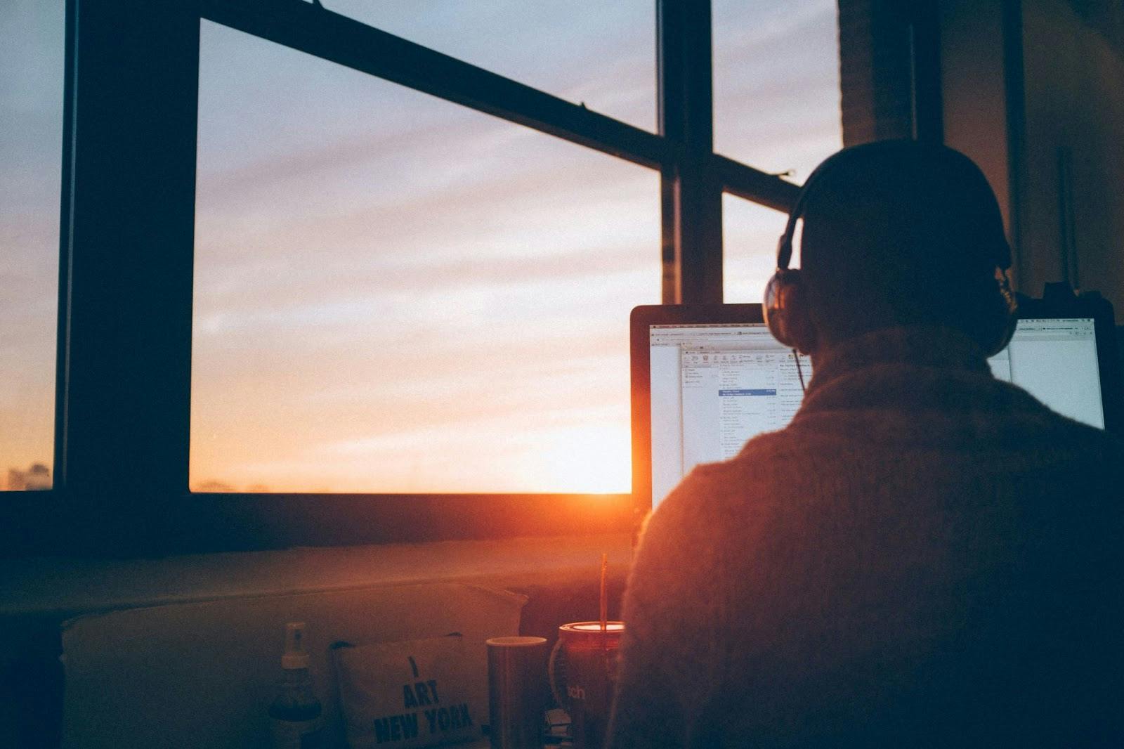 a man works from his laptop at sunset