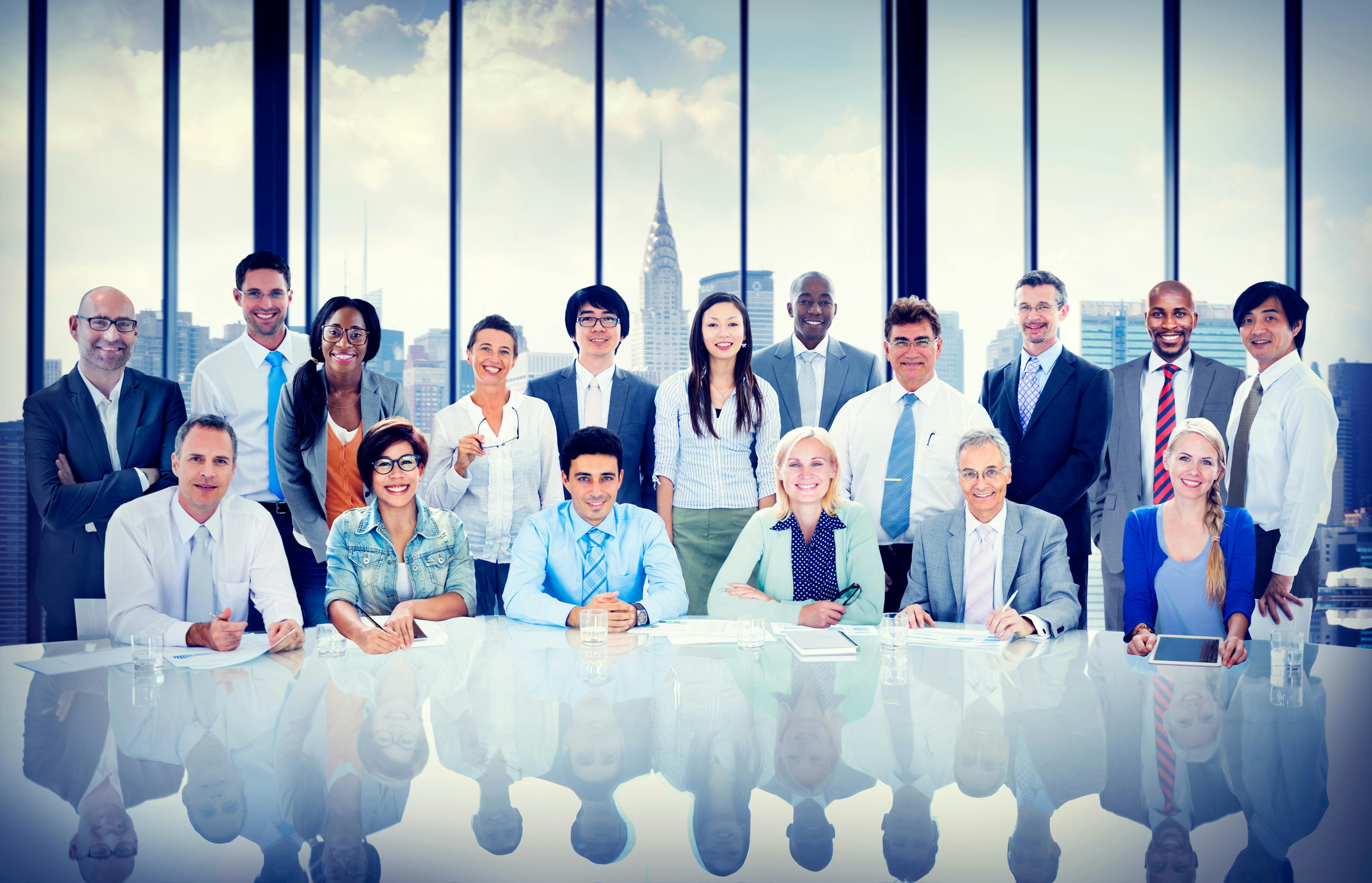 A group of diverse candidates sit around a conference table with a city skyline in the background