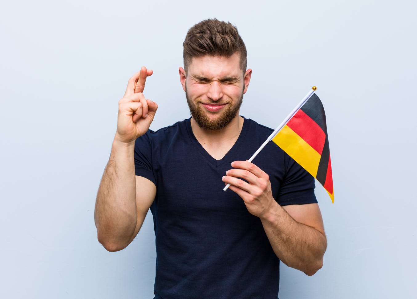 Man hoping to relocate to Germany via Chancenkarte crossing his fingers and holding German flag.