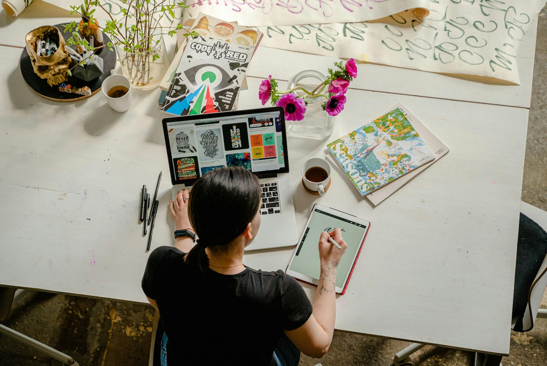 Woman in front of computer and tablet designing her next social posts.