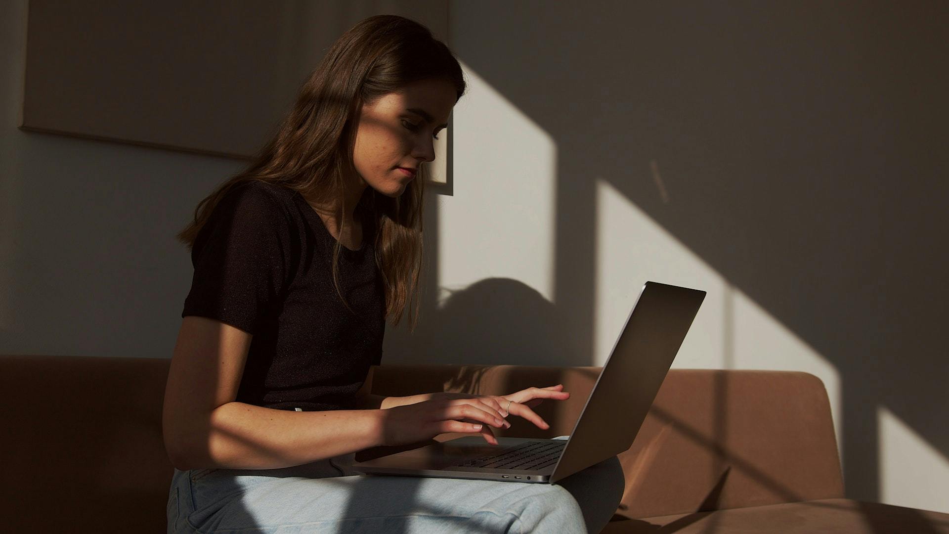 Woman sitting on couch on a laptop browsing social media.