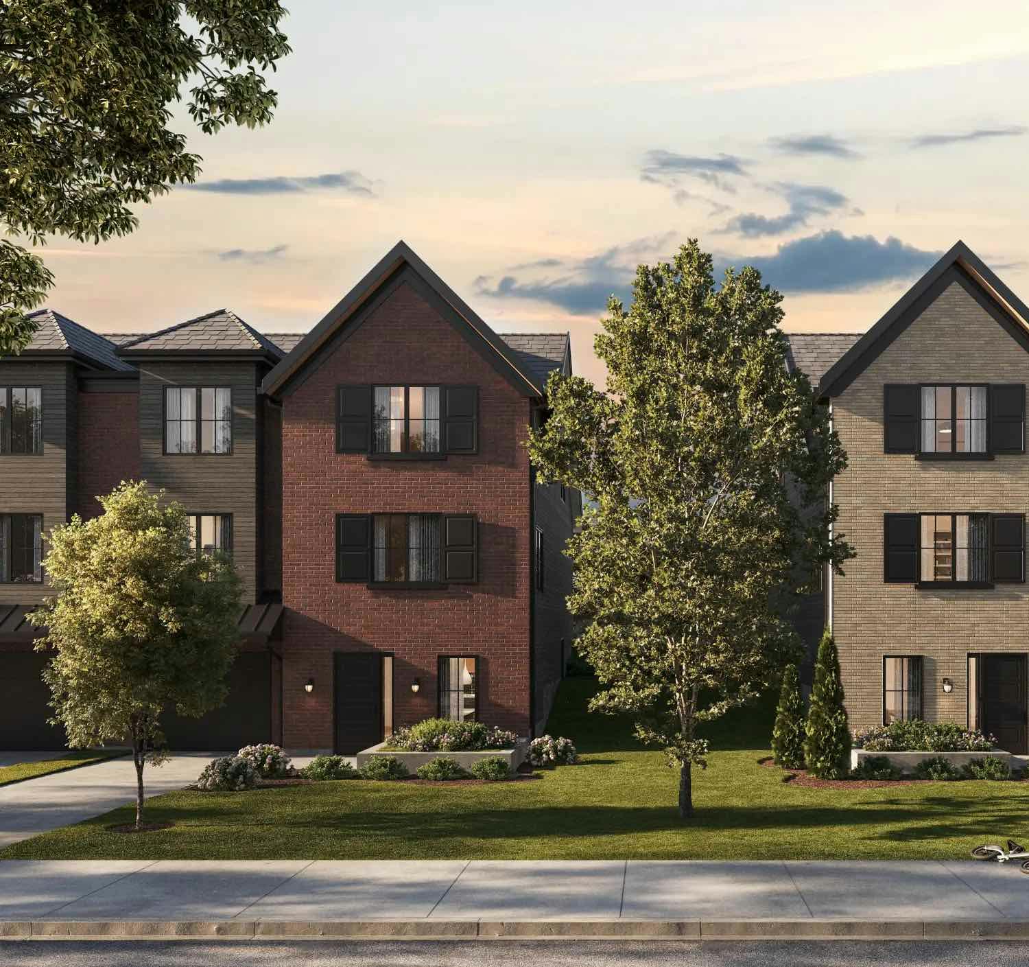 A row of modern townhouses with trees and a grassy front yard, set against an evening sky