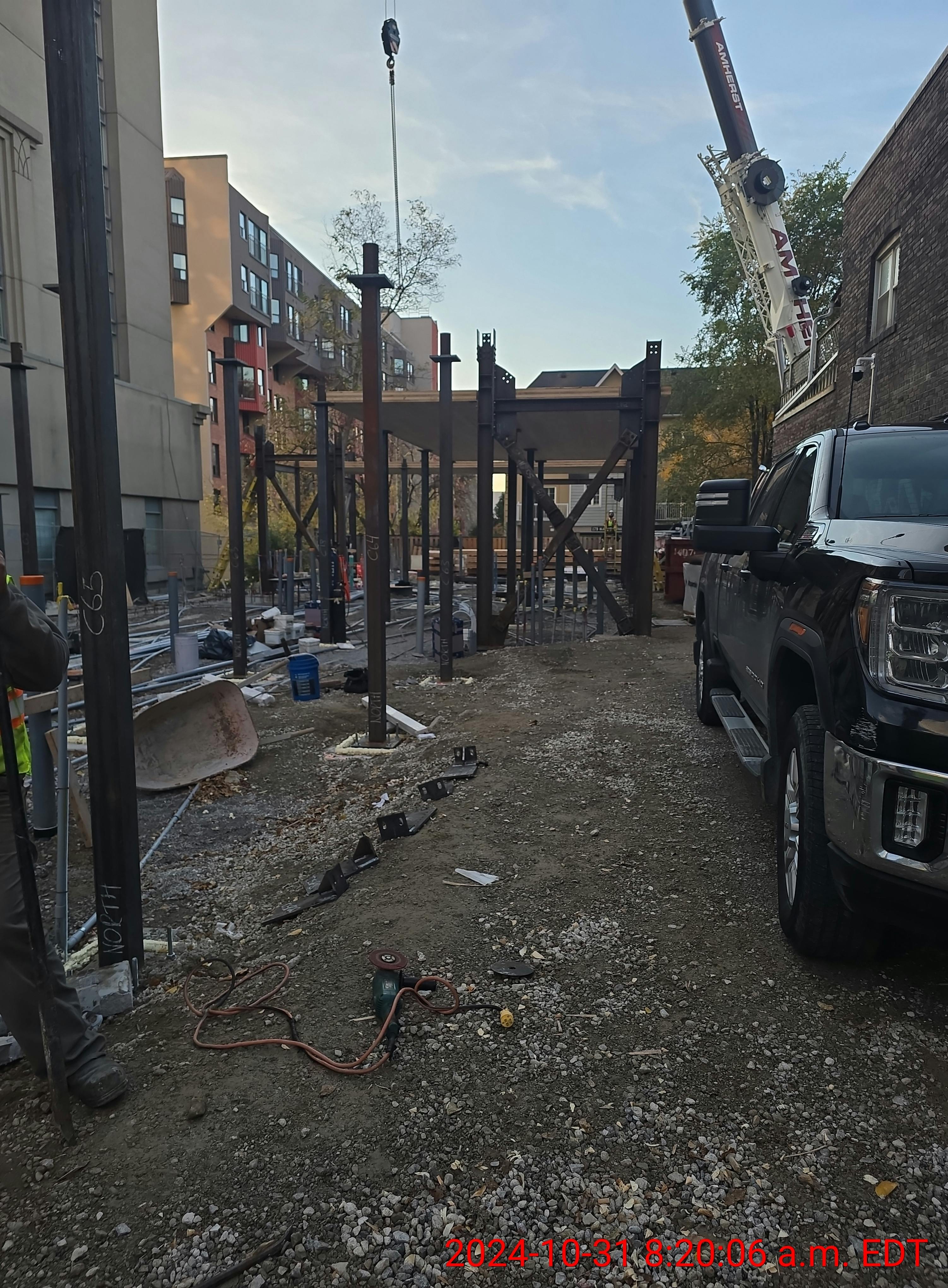 Excavation site at 215 Wellesley St. with construction materials, crane, and vehicle in the background