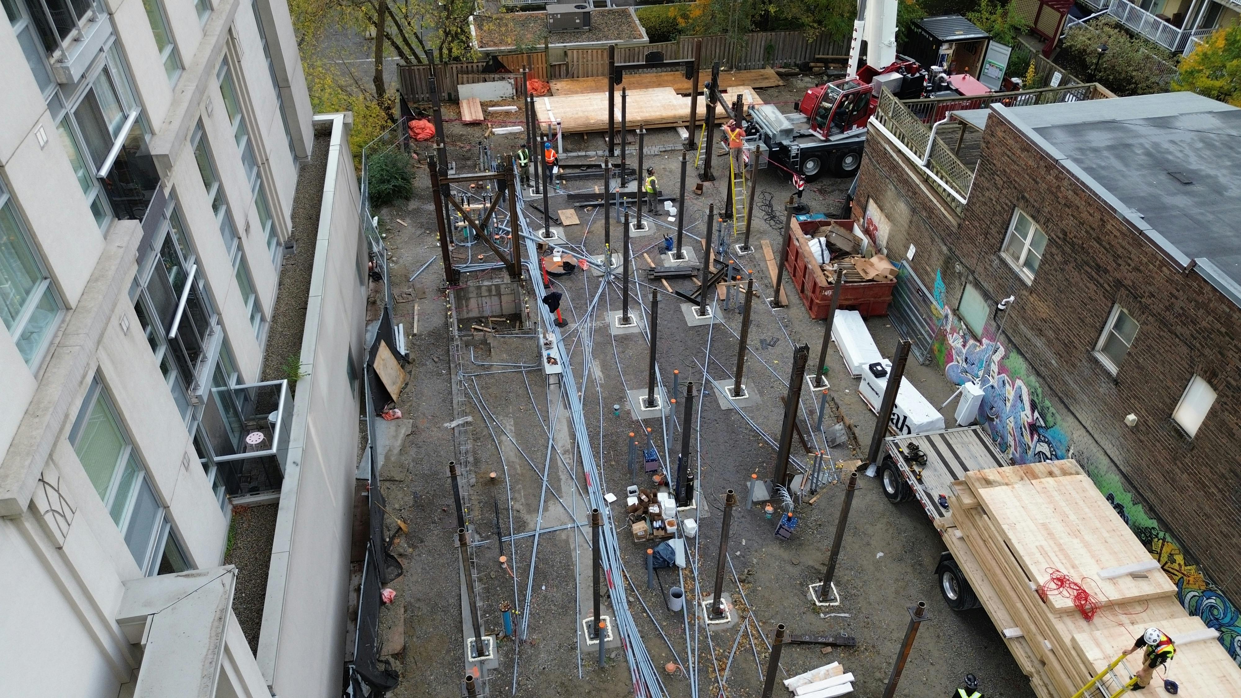 Aerial view of 215 Wellesley St. with construction workers on site, vehicle in the background