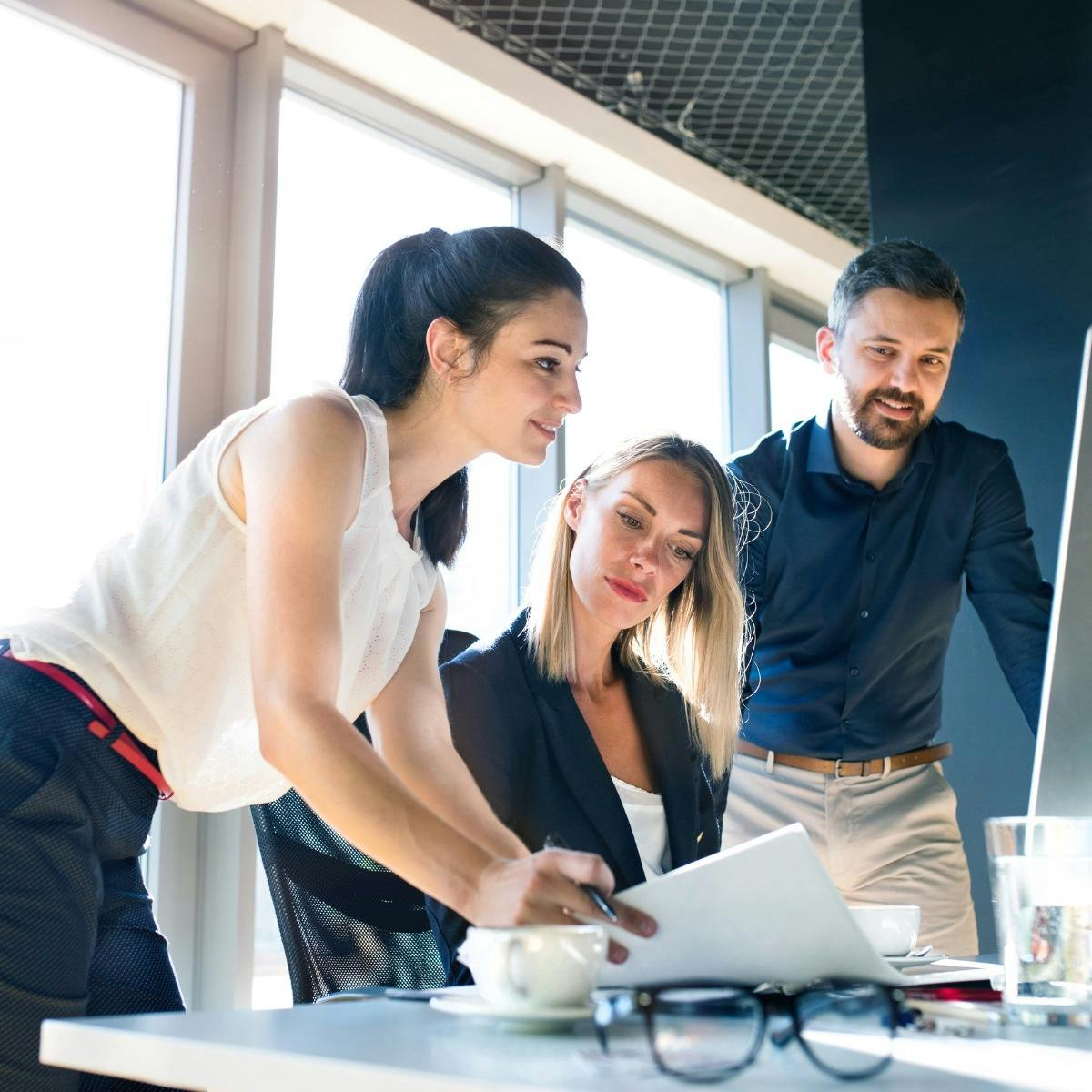 Three retail employees reviewing time and attendance dashboards