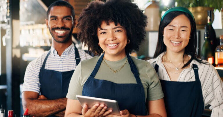 Store employees smiling holding a tablet