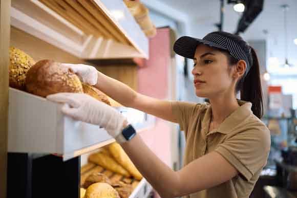 Fresh baked goods department employee selecting bread for a customer