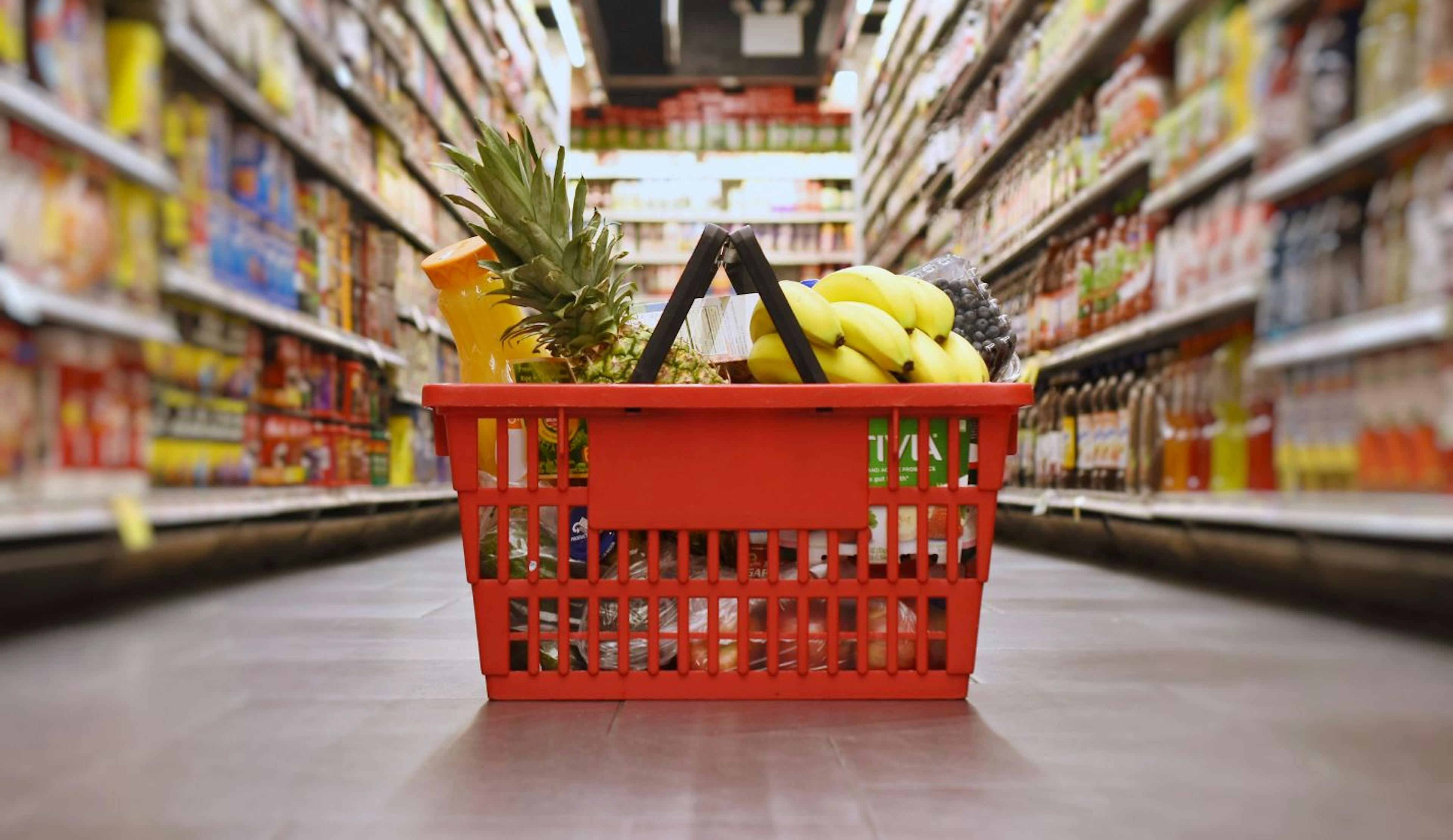 Grocery basket filled with fresh food items in grocery store aisle 