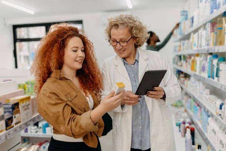 Happy Pharmacist using tablet to help customer