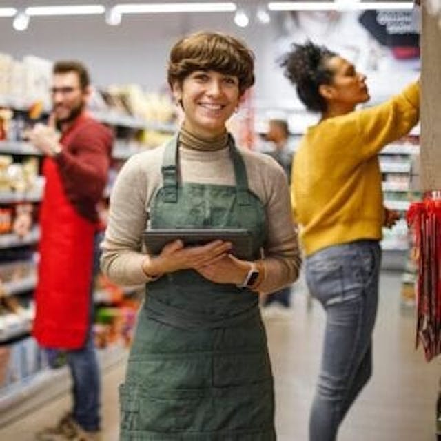 Smiling grocery associate holding tablet